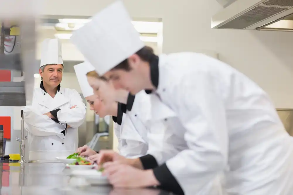 culinary instructor watching his students plate a dish