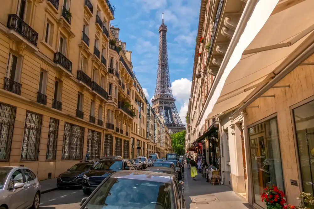 A street-level view of a Paris neighborhood with the Eiffel Tower in the background