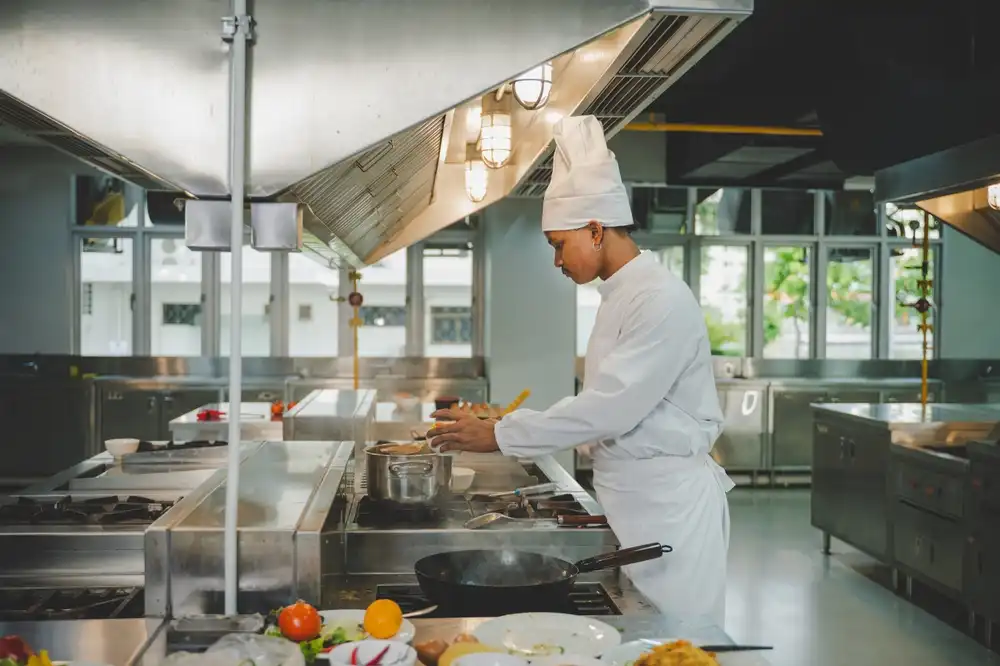 A student chef at the Culinary Institute of America (CIA) campus in Hyde Park, New York, preparing food in a professional kitchen.