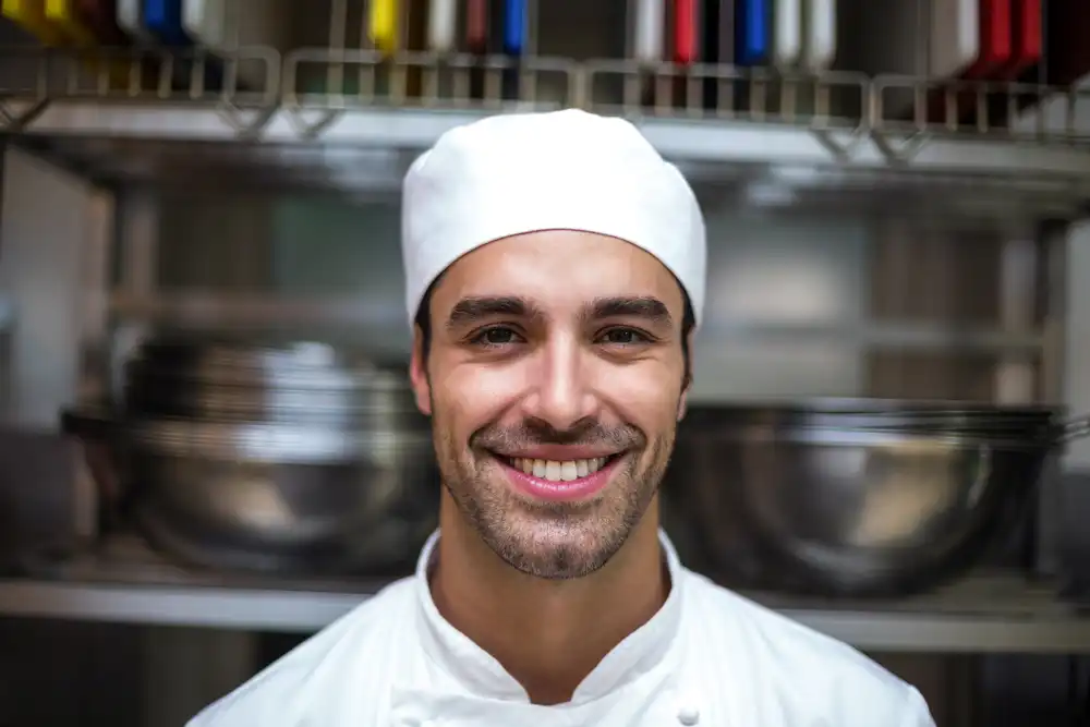 A smiling culinary school student who has chosen to study in Paris, France.