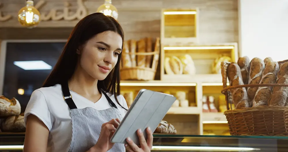 Allocating a budget for digital marketing is crucial for restaurants to effectively reach their target audience and achieve their marketing goals. This image shows a restaurant owner looking at at a budget plan on her tablet as part of digital marketing restaurants.