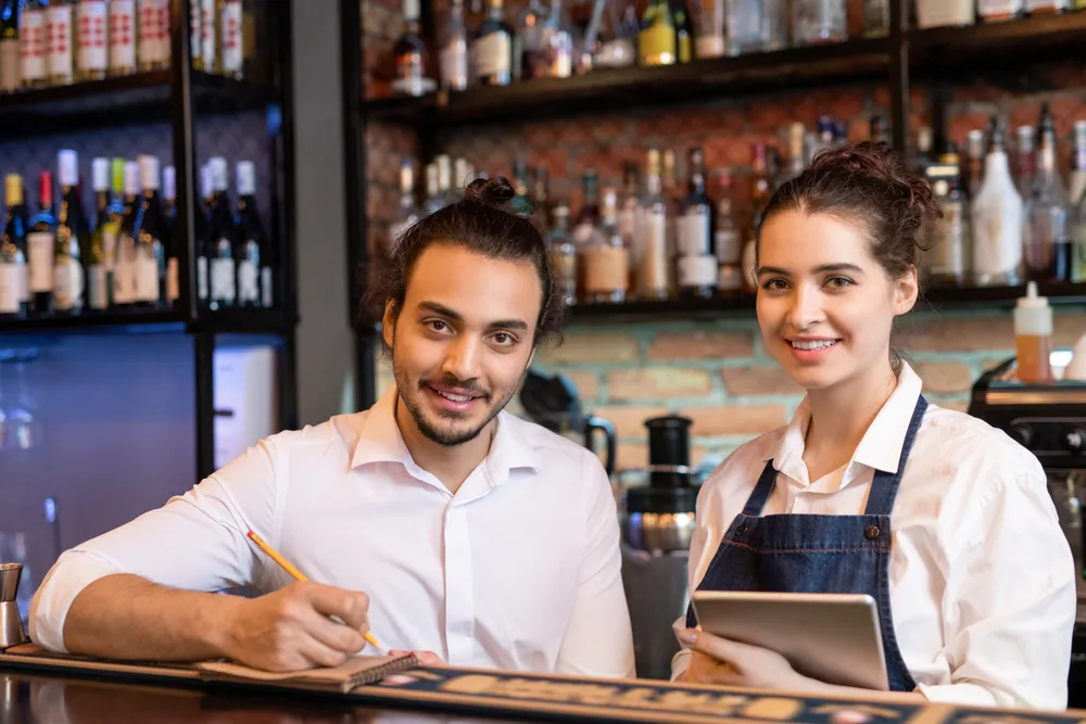 Two restaurant owners stop for a minute to pose for a photo in their restaurant. TikTok digital marketing for restaurants can include showcasing the people behind the business.