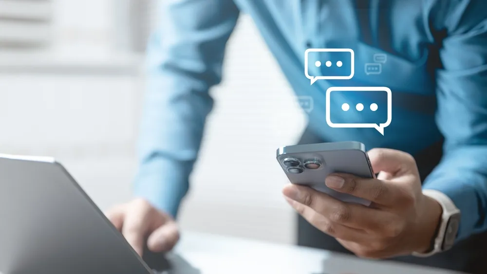 A restaurant owner checks both his laptop and smartphone for social media engagement. TikTok digital marketing for restaurants can include engaging with comments and turning them into content.