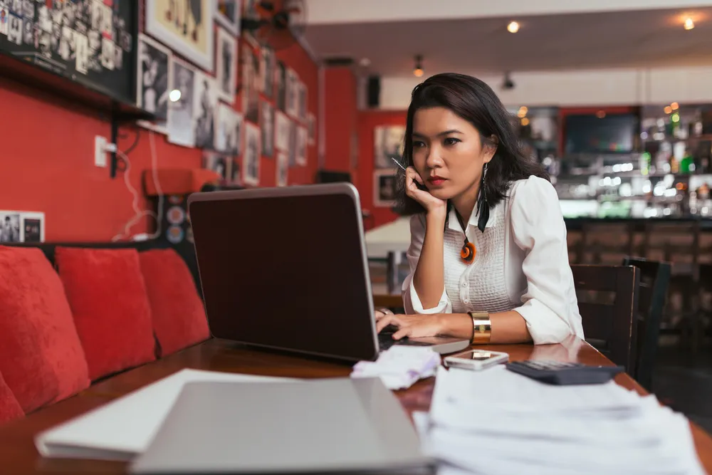 A restaurant owner working on a laptop as she plans her email marketing campaign for the next 30 days
