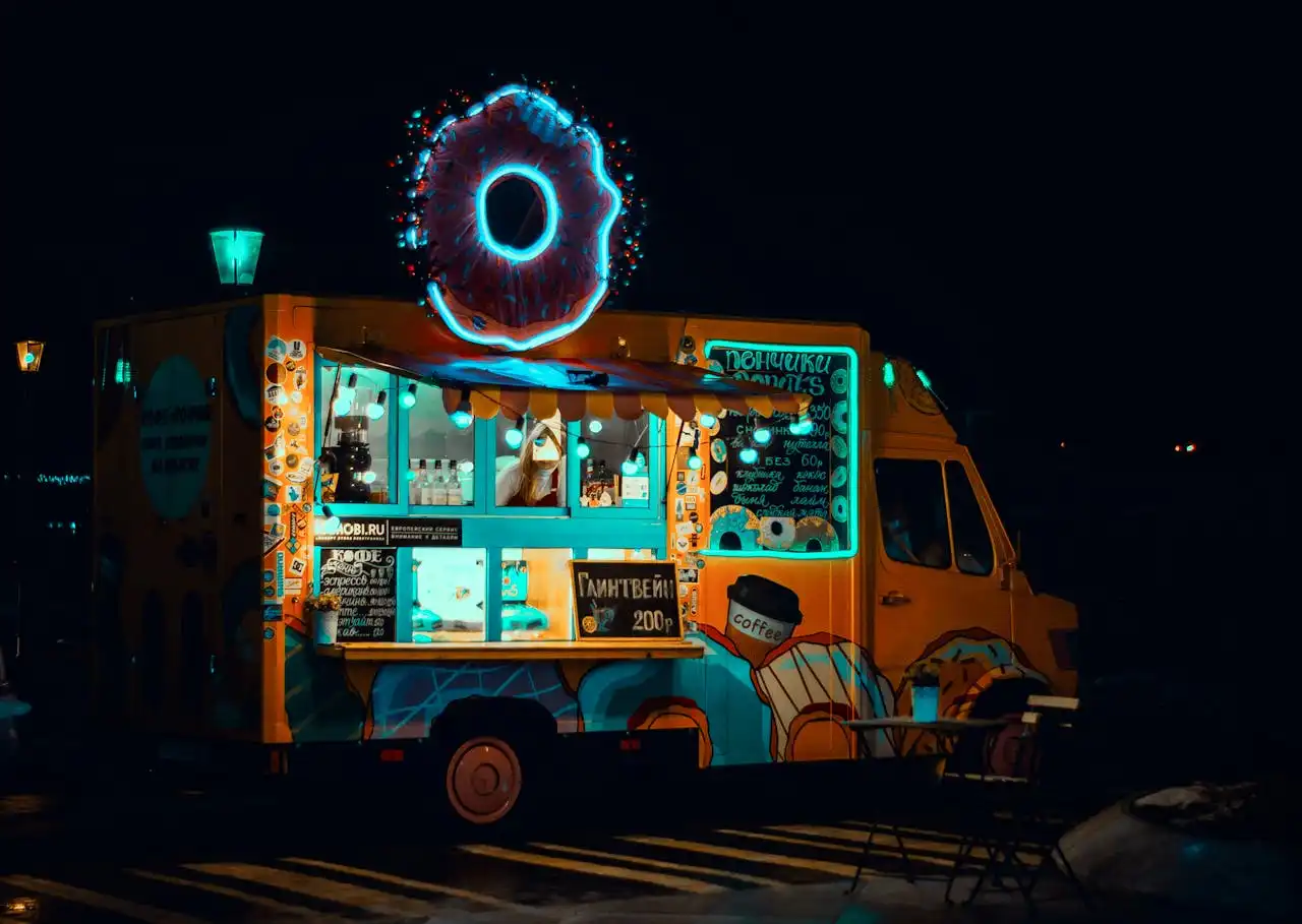 A food truck that sells donuts. Night time.