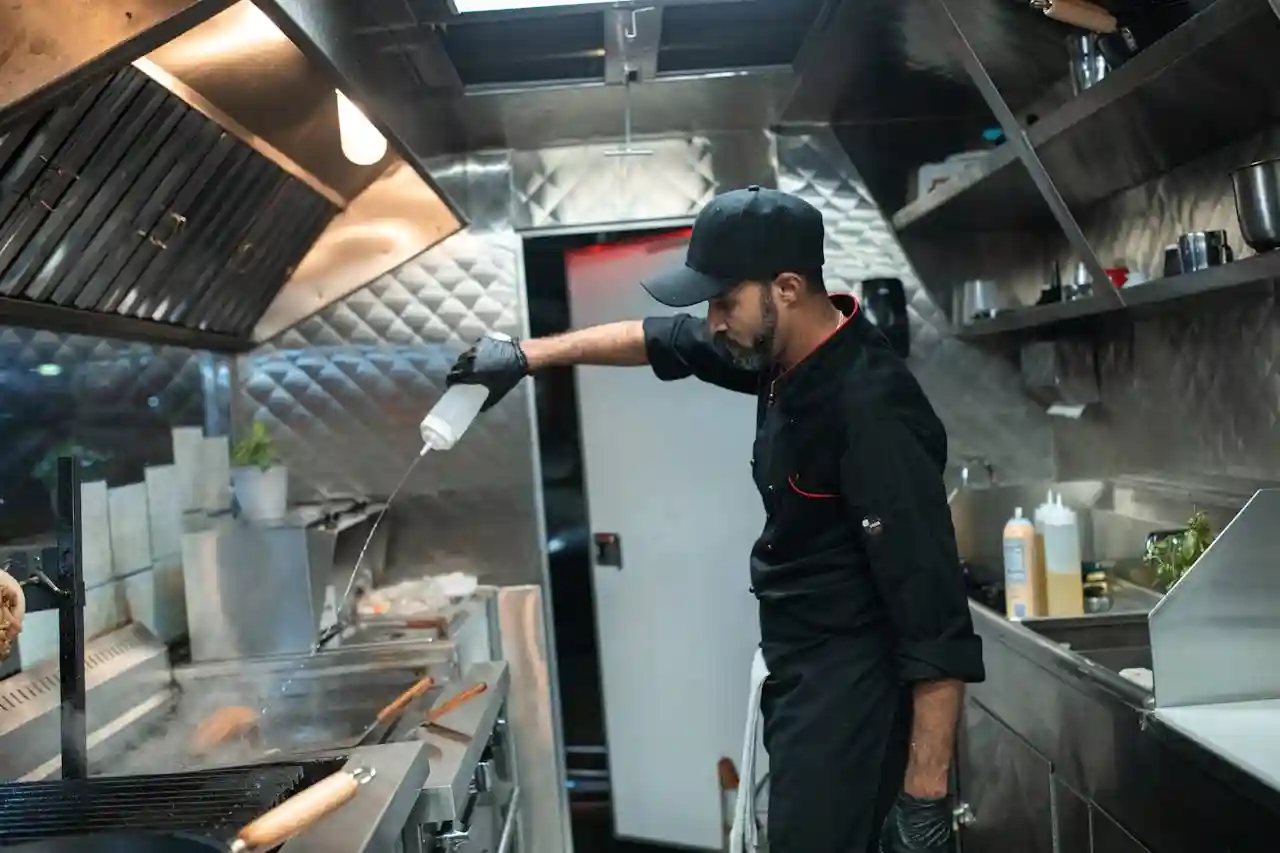 A cook in his food truck cooking over a griddle