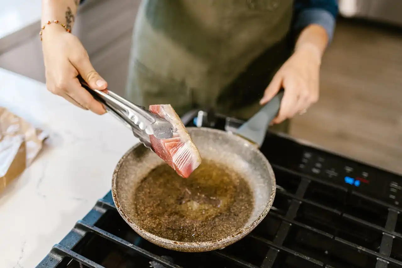 Chef privado cocinando un trozo de pescado en una sartén