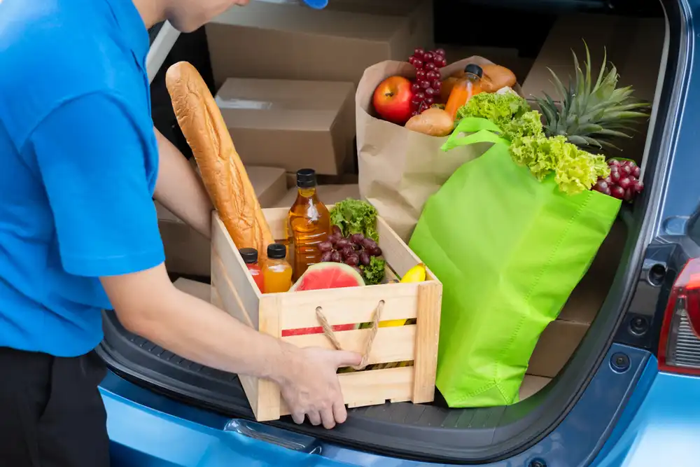 Chef privado cargando comestibles en la parte trasera de su auto