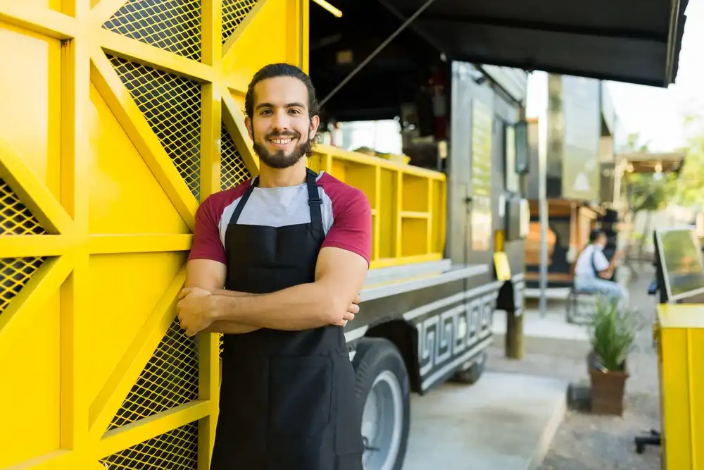 The owner of a food truck business poses for a photo in front of his new food truck.