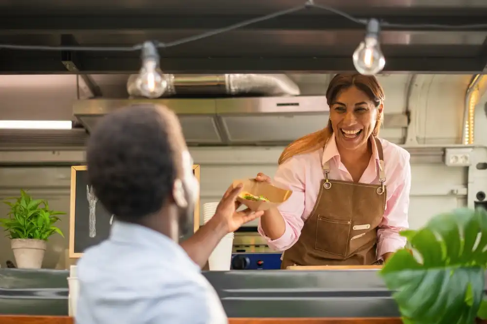 A food truck business owner in Austin, TX serving one of her customers