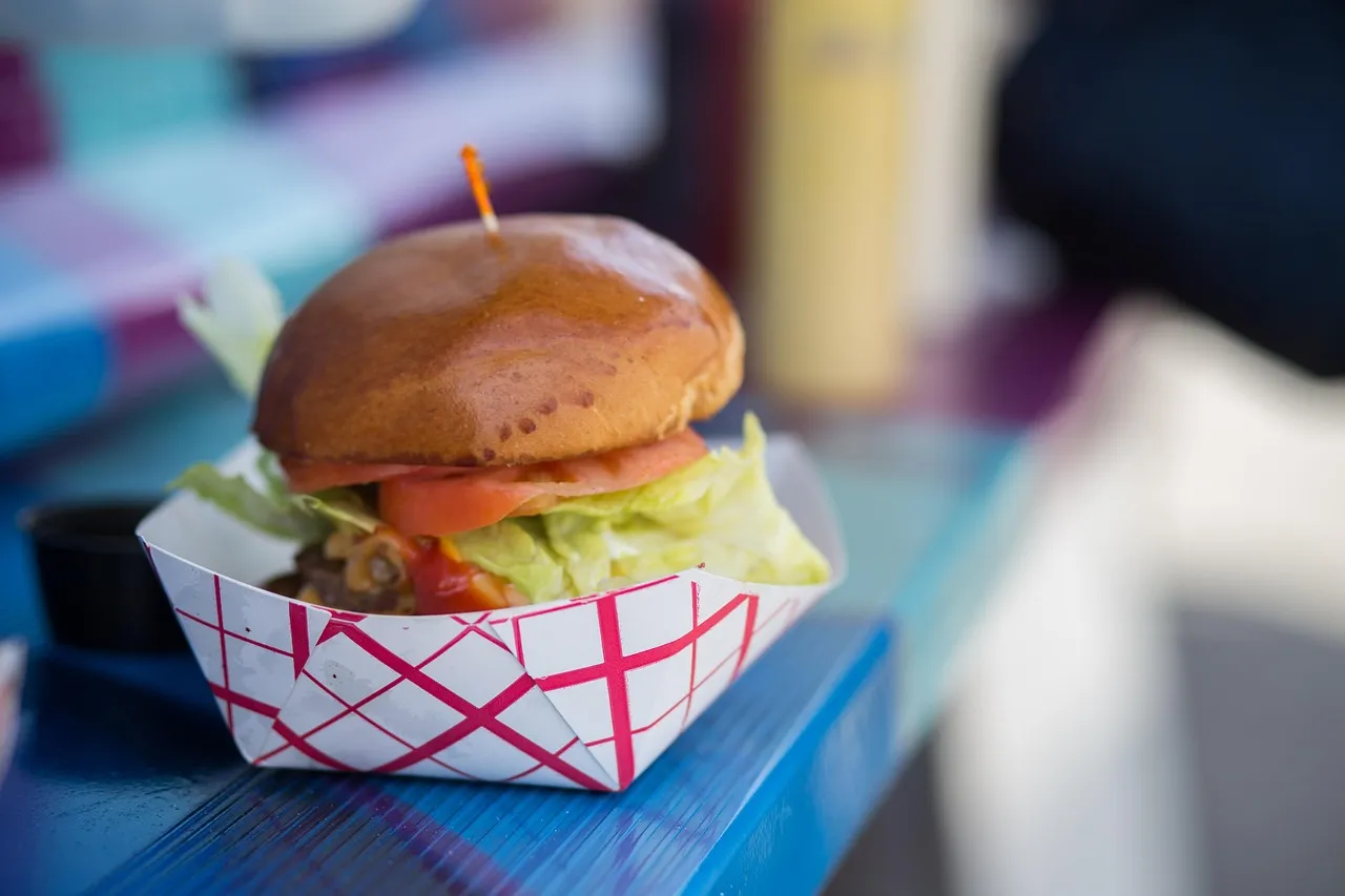 Cheeseburger in a to-go paper tray. Menu items such as this are popular in food trucks Miami.