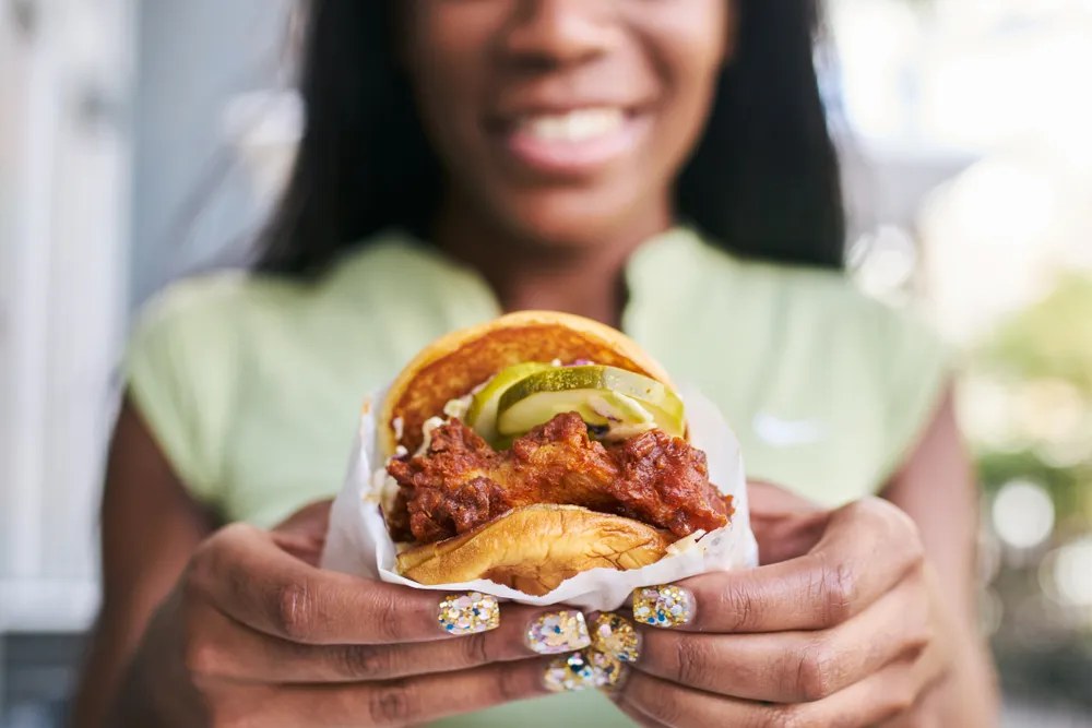 A female customer shows her Nashville hot chicken sandwich from a food truck in Nashville, Tennessee. The city's vibrant food scene makes it an ideal market for food trucks.