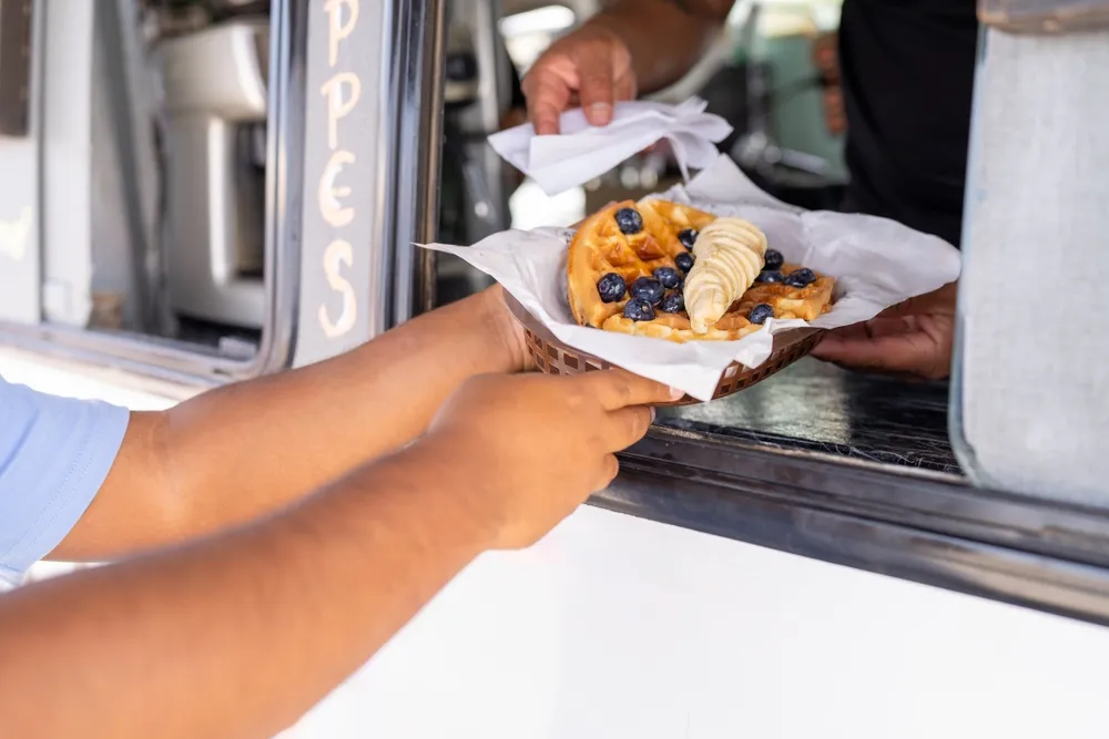 A customer receives his order of waffles from a Nashville food truck. As part of starting a food truck business in Nashville, Tennessee, you must get your permits and licenses in place, including a mobile food unit permit from the city.