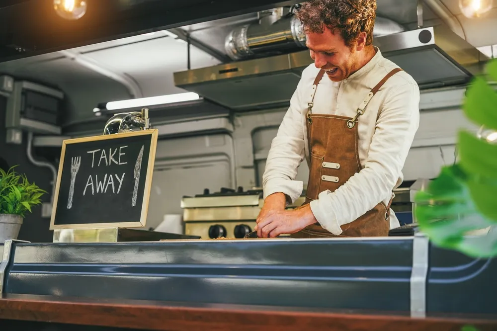 A food truck operator in Phoenix, Arizona, serving customers from his colorful food truck.