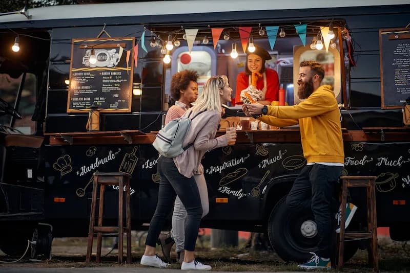 Happy food truck customers enjoy their meals at an outdoor seating area in Portland, Oregon.