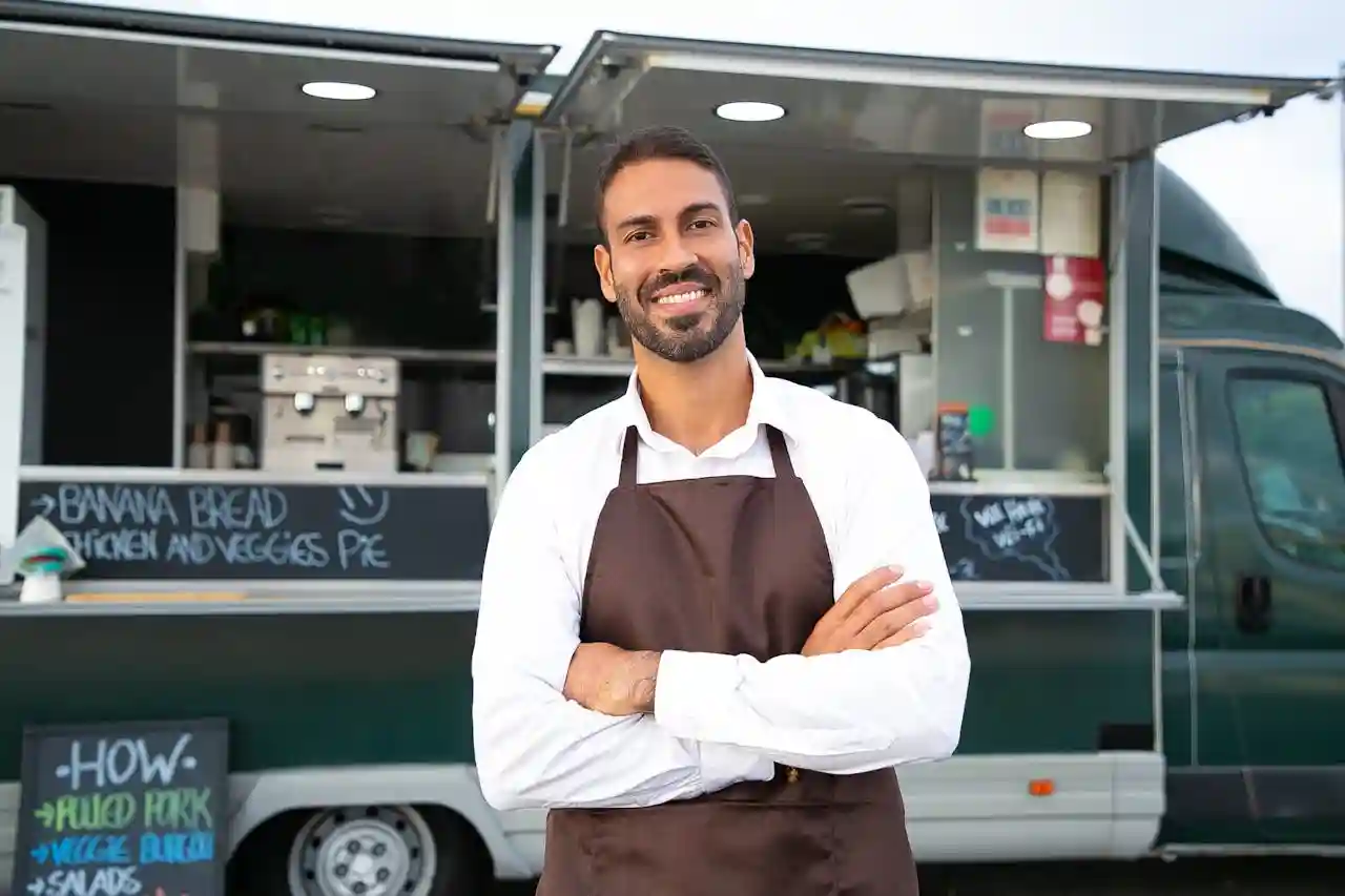 Chef de pie frente a su camión de comida que le sirve de restaurante popup