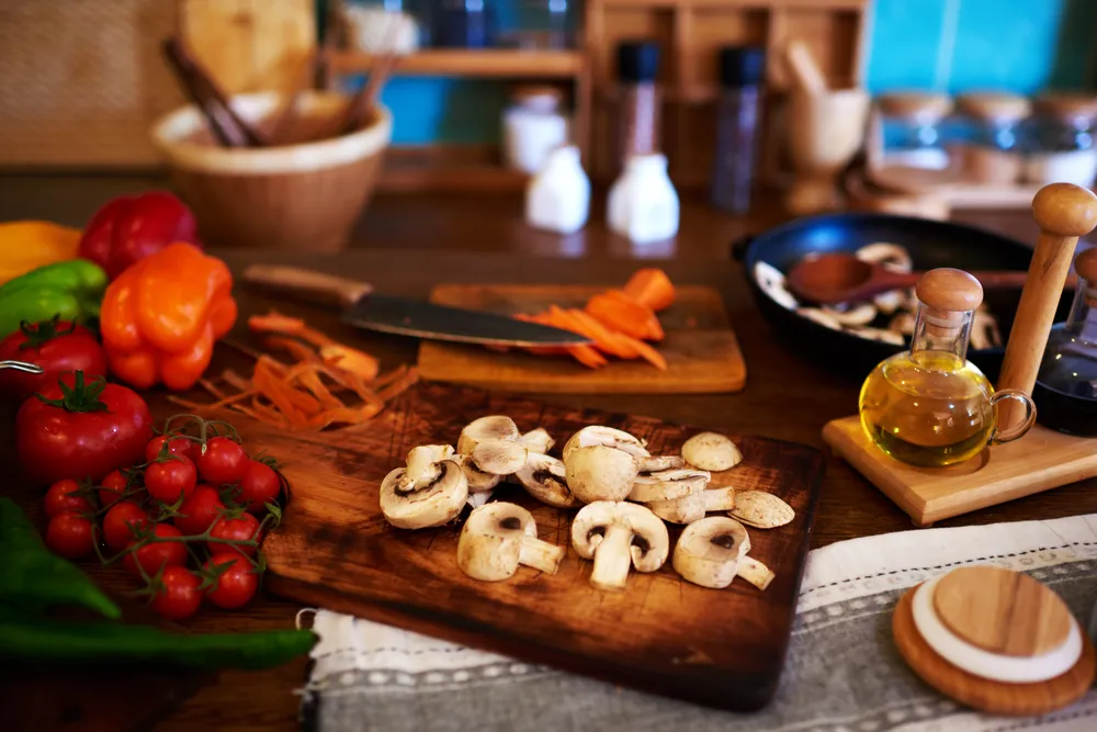 Una mesa de preparación de alimentos de cocina con varios ingredientes y utensilios y tablas de cortar.
