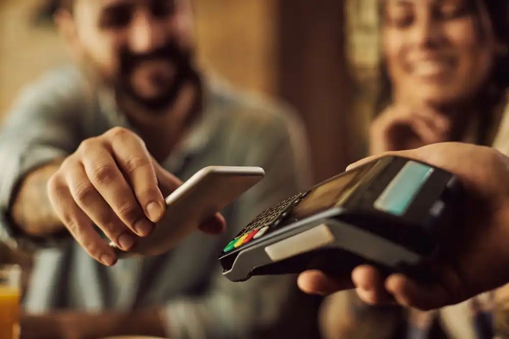 Un cliente puede usar su teléfono o tarjeta de crédito en una terminal sin contacto que forma parte de un sistema POS en un restaurante.