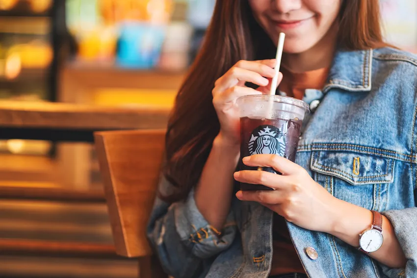 A customer in a Starbucks cafe enjoying an iced beverage. Even after 50 years, Starbucks continues to be a popular coffee brand worldwide with many lessons to offer to restaurateurs.