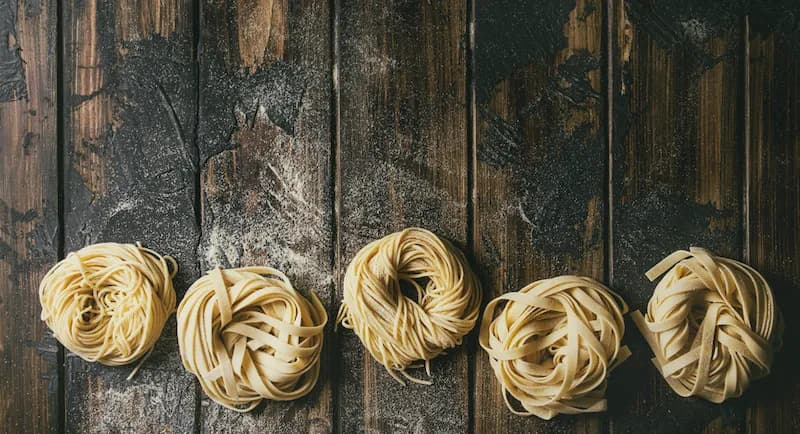 Various types of handmade pasta on a wooden table. Culinary school students in Italy learn to make traditional Italian dishes like pasta from scratch.