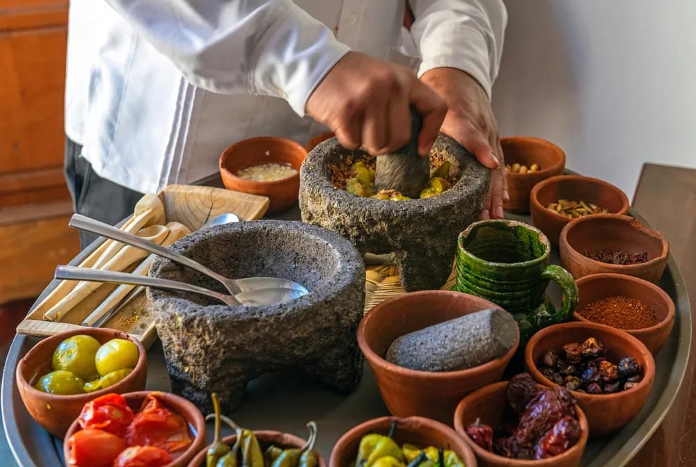 A Mexican chef preparing salsa macha in a traditional molcajete. Mexican cuisine is recognized as a UNESCO Intangible Cultural Heritage of Humanity.