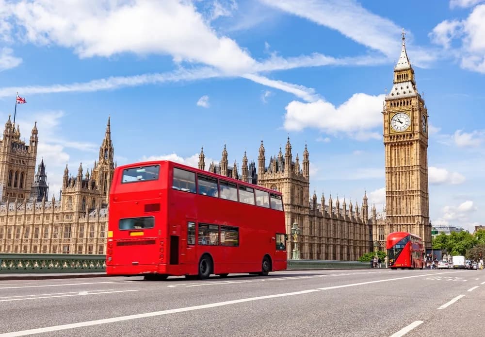 Un autobús rojo de dos pisos circula cerca del Big Ben en Londres, Reino Unido. Exploremos algunas de las mejores escuelas de gastronomía del Reino Unido.