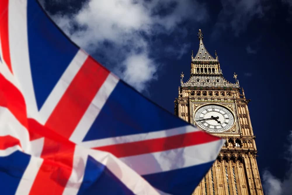 La bandera británica ondea en primer plano, con el emblemático reloj Big Ben al fondo. El Reino Unido alberga algunas de las mejores escuelas de gastronomía del mundo.