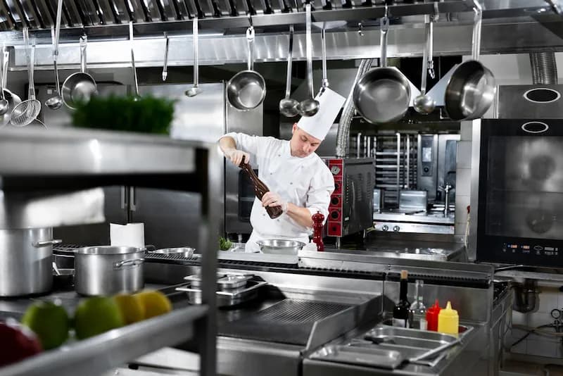 A chef works in his restaurant's kitchen where both new and used commercial kitchen equipment is utilized. Buying used commercial kitchen equipment can save restaurant owners thousands of dollars when opening a new restaurant.