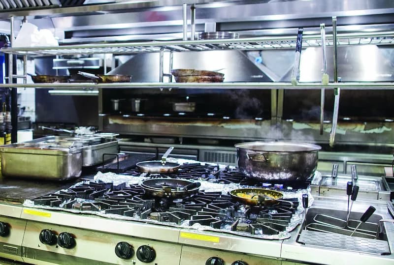 A professional restaurant kitchen with various used commercial kitchen equipment including a stove, oven, and stainless steel prep tables. Buying used restaurant equipment can save you thousands of dollars when opening a new restaurant.