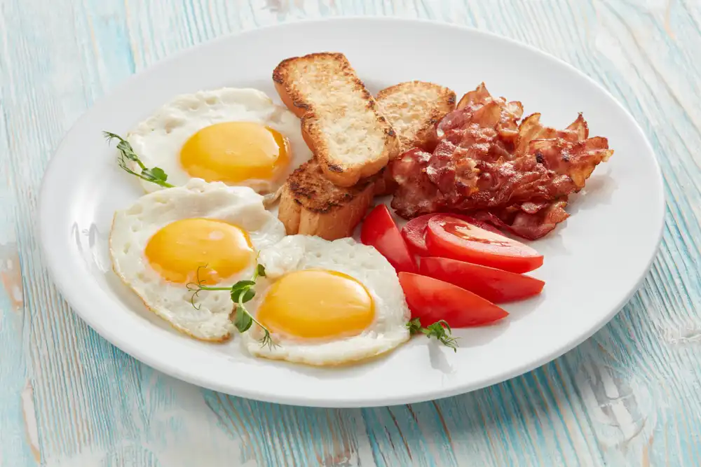 Otro plato de desayuno tradicional con huevos, panqueques y salchichas. Esta imagen del menú comparte un estilo de iluminación y composición similar al de la primera foto, creando una marca visual consistente en el menú del restaurante.