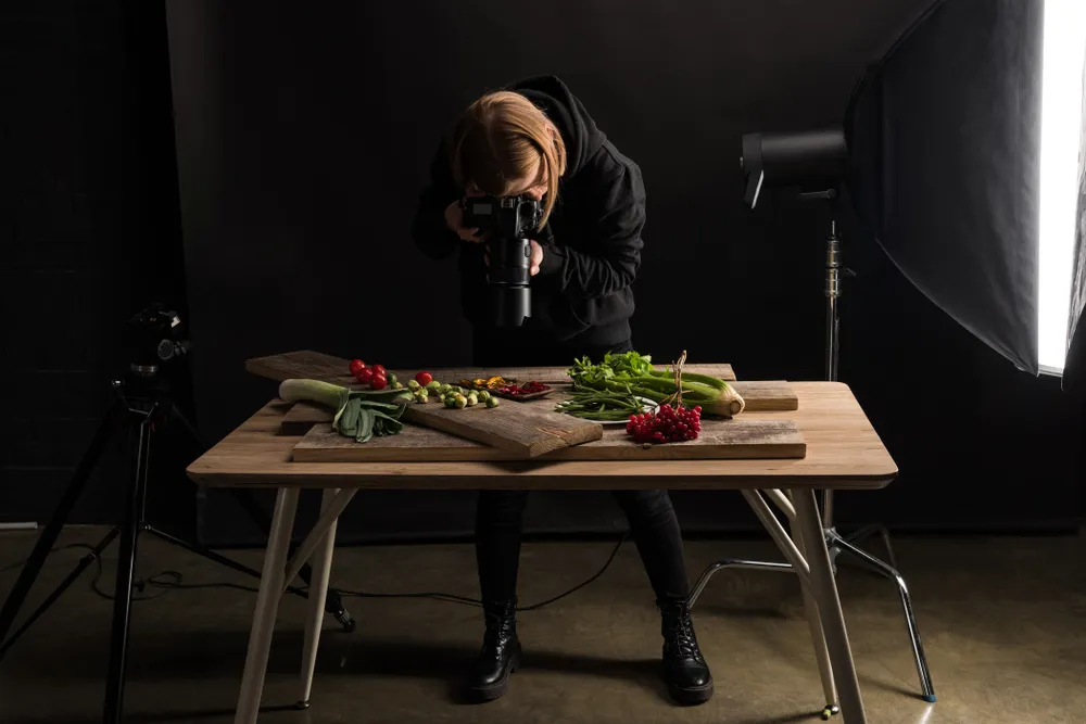 Un fotógrafo gastronómico profesional toma fotografías de un plato gourmet en un restaurante. La fotografía gastronómica de alta calidad puede mejorar significativamente el atractivo visual de los platos del menú y atraer a más clientes.