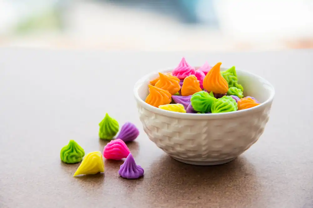 Un pequeño tazón lleno de dulces se ve nítidamente enfocado. El fondo está desenfocado a propósito. Al usar un enfoque nítido, la imagen de un menú puede atraer la atención del espectador hacia el plato.