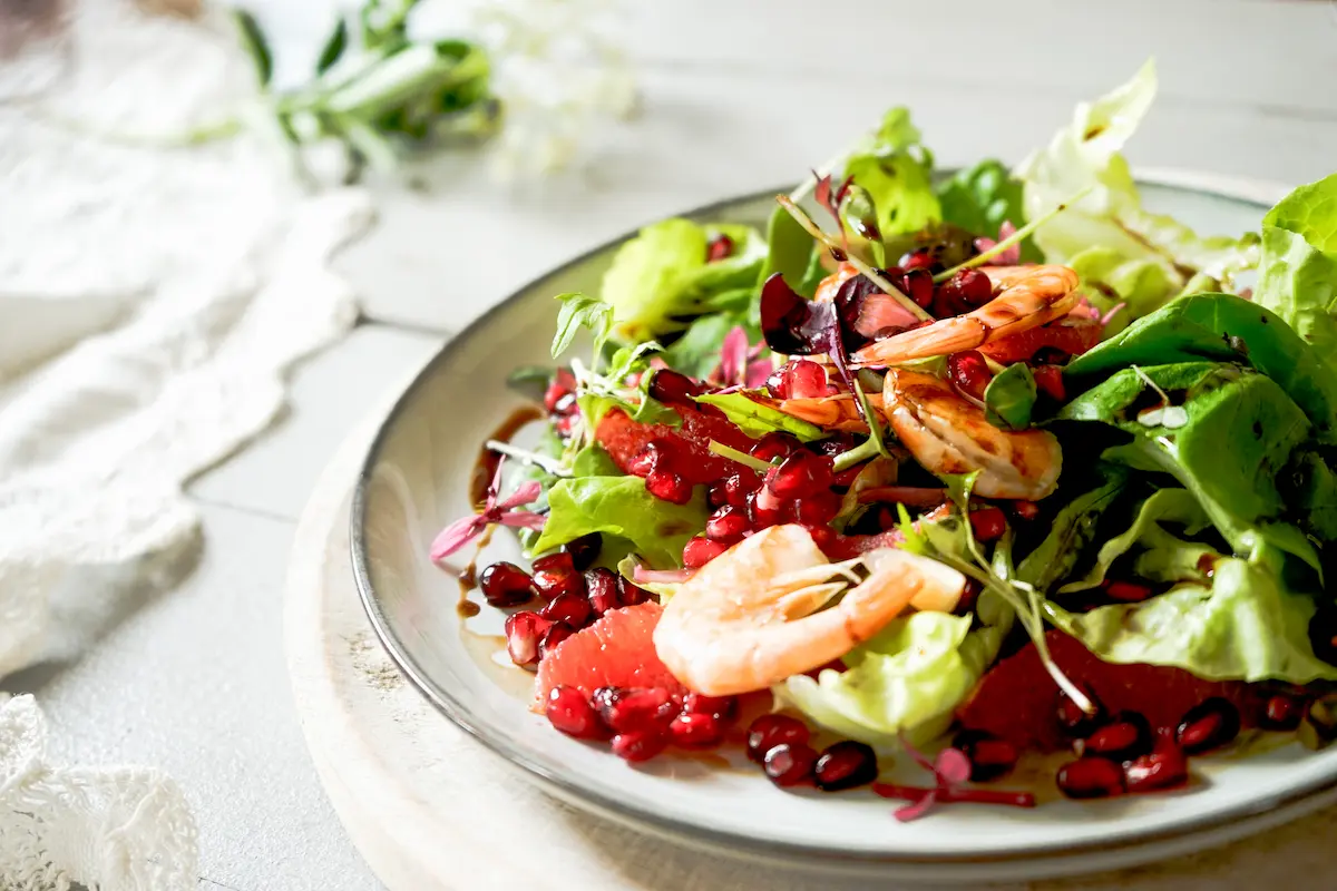 Los estilistas de alimento utilizan una variedad de técnicas para hacer que la comida luzca deliciosa, como se muestra en esta foto de una ensalada con camarones y granada.