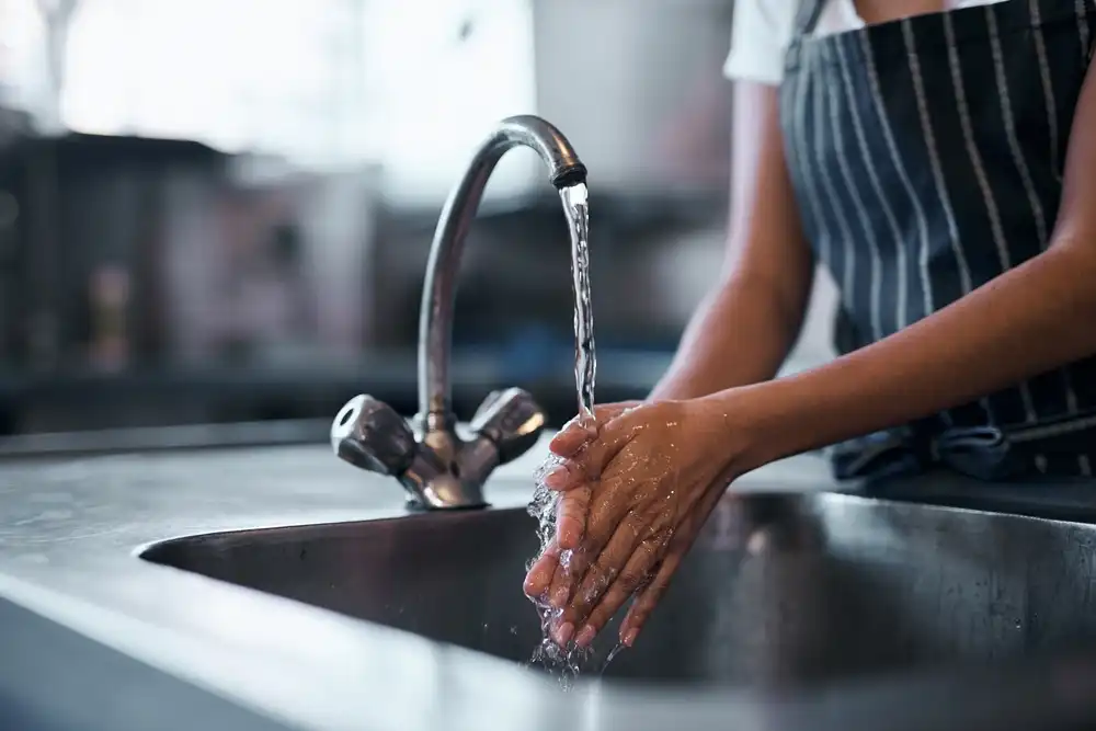 Health and safety regulations are important to consider when evaluating how to start a ghost kitchen. As shown in this image of a chef washing her hands in her ghost kitchen.