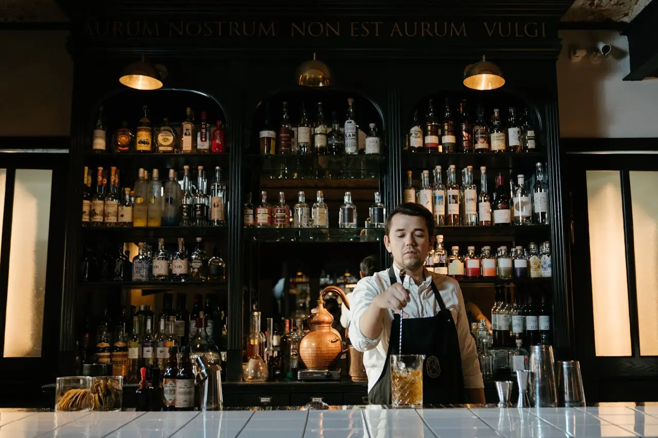 Bartender serving drinks. Bartenders are the face of the bar, serving drinks quickly and efficiently, as shown in this image of a bartender at this bar cleaning a glass and preparing drinks.