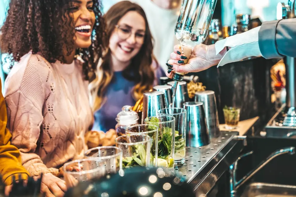The skills needed to be an ultimate mixologist are varied and chief among them is accurate pouring as shown in this image of a mixologist pouring drinks for her guests.