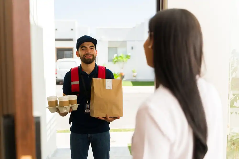 The best food delivery app for a restaurant in Latin America is one that has a strong presence in the local market, such as Rappi, iFood, or PedidosYa. Image of a food delivery operator delivering food to a happy customer.