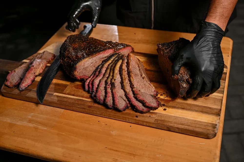 Texas-style smoked brisket from Franklin Barbecue on a wooden cutting board, with a slicing knife alongside it.