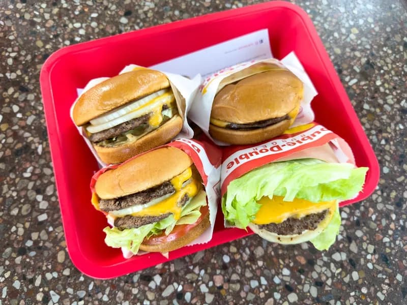 A red tray containing four In-N-Out burgers including a cheeseburger and the popular double-double.