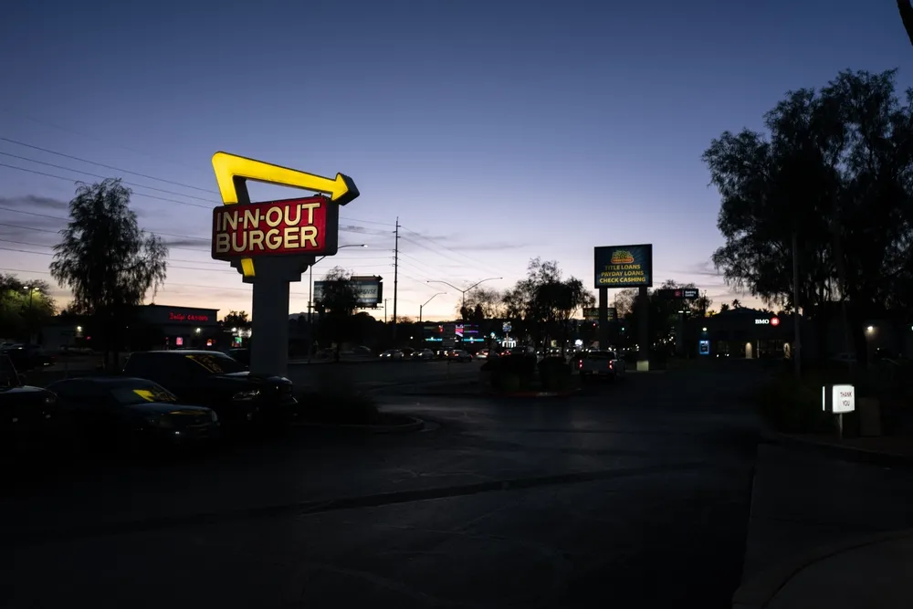 The In-N-Out Burger logo is illuminated to signal the restaurant is open on a Southern California evening.