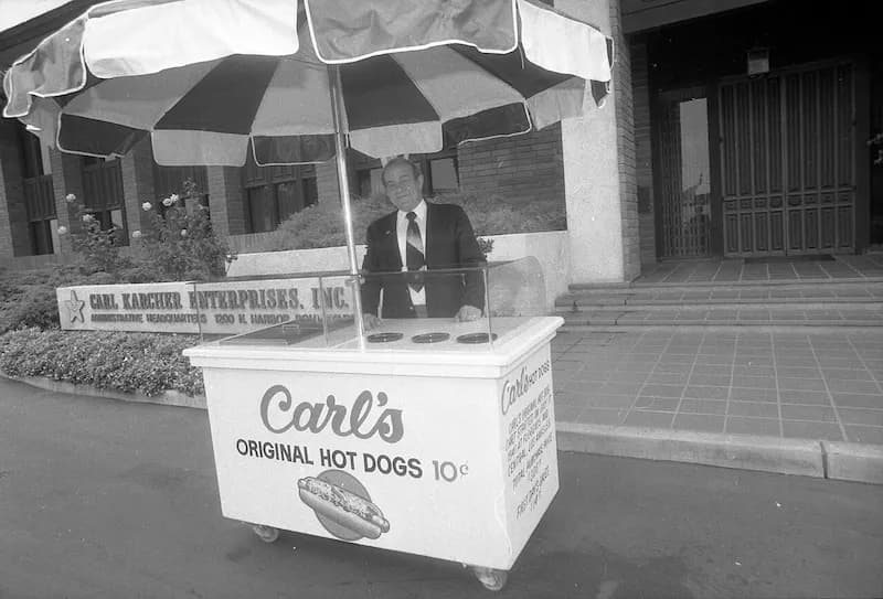 Carl Karcher poses behind a replica of his original hot dog cart, which he purchased in 1941 to start what would become the Carl's Jr. chain of fast food restaurants.