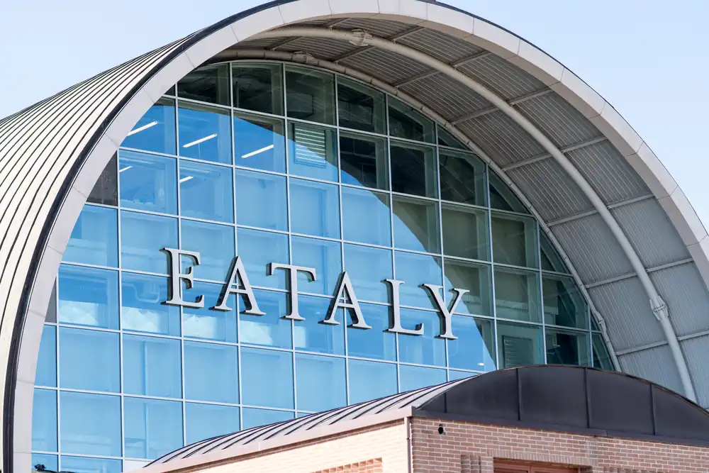 La fachada de vidrio y la señalización de la ubicación de Eataly en Roma, que muestra su diseño arquitectónico moderno que invita a los clientes a explorar la auténtica cocina y cultura italiana.